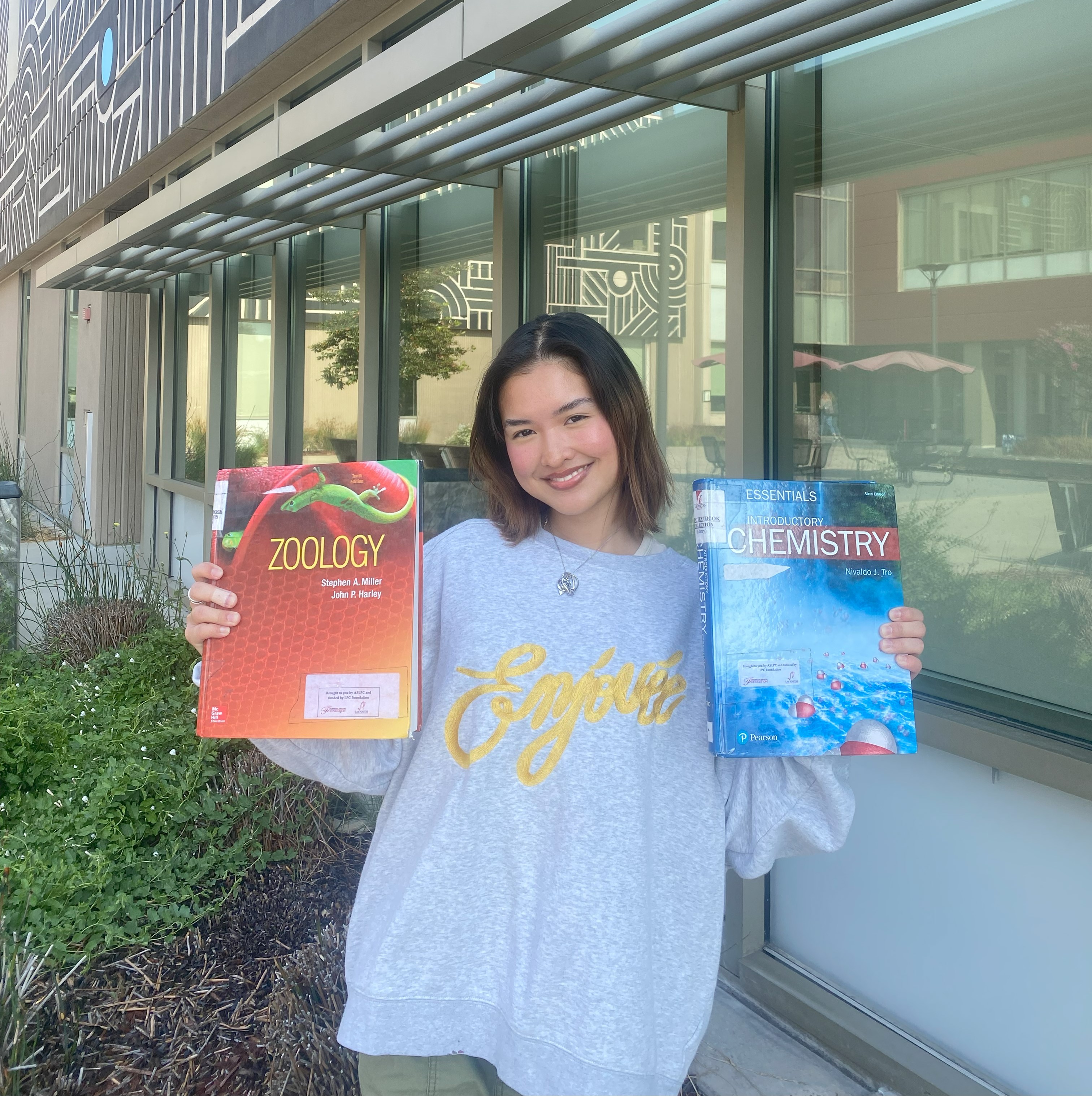 student holding up a zoology textbook and a chemistry textbook